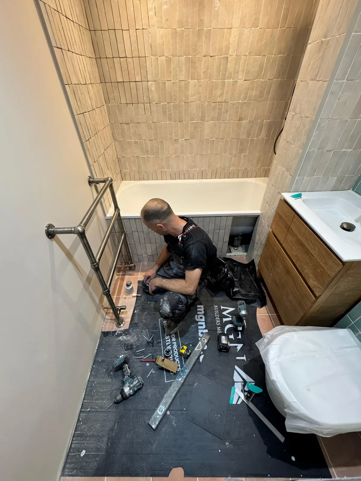 An A&G installer fitting a bathroom in a London home, with floor protection down and tools laid out
